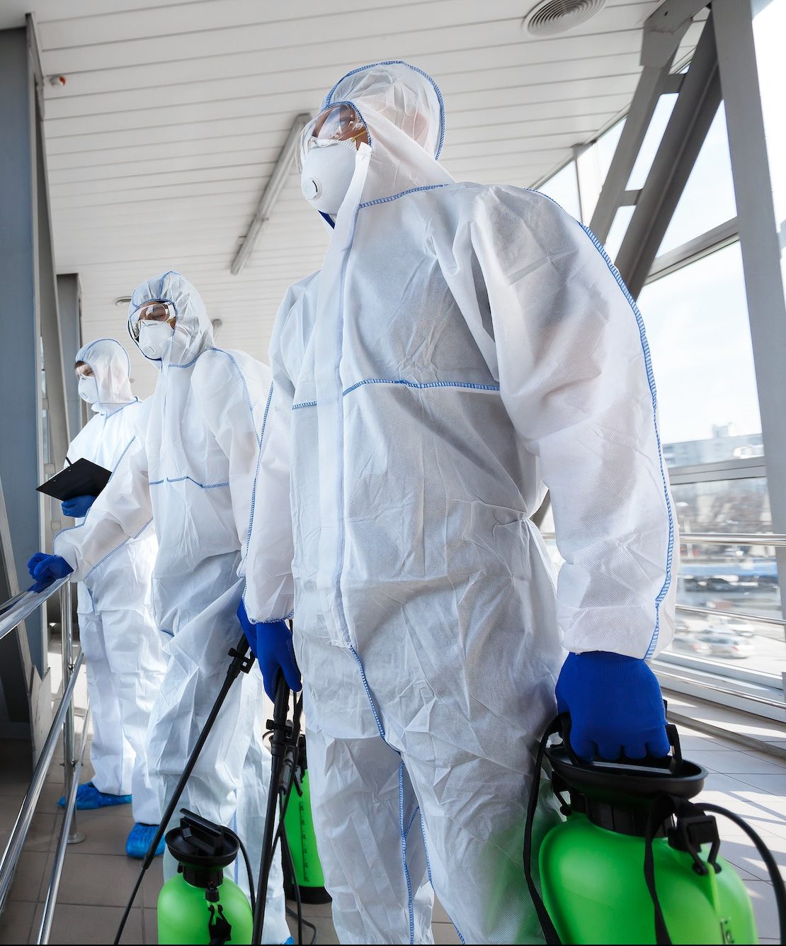 Medical workers in hazmat suits disinfecting with spray public places